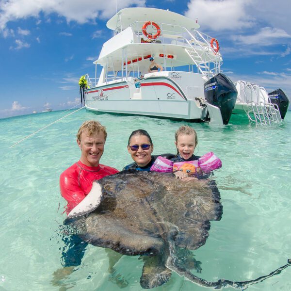 Man, woman, and child with stingray in the water