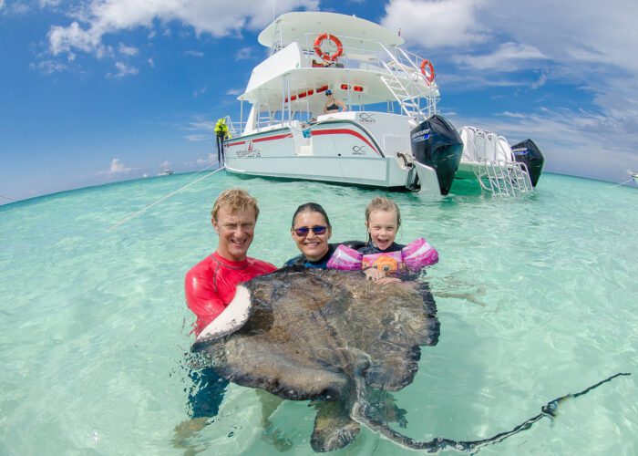 Man, woman, and child with stingray in the water