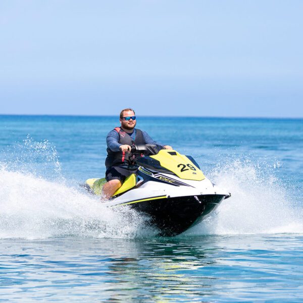 At the Rum Point Beach Club, a man enjoys riding a jet ski in the ocean while savoring refreshing cocktails on the Rum Deck.