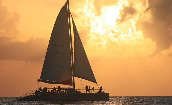 A catamaran sails in the ocean during a stunning sunset