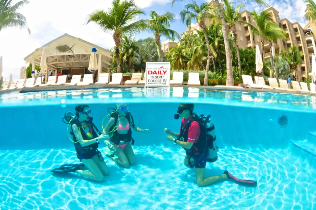 Three people in scuba gear learning diving in swimming pool in the Cayman Islands.