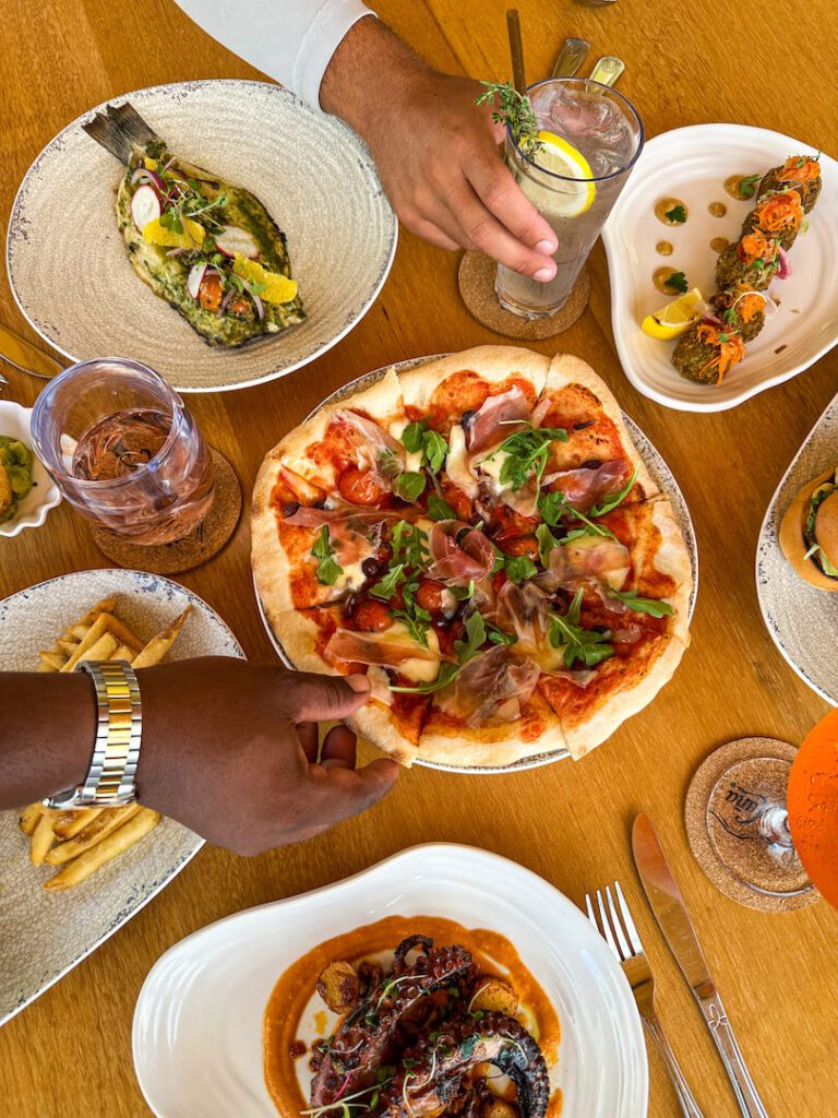 Pizza, fish, octopus, appetizers and drinks on a restaurant table