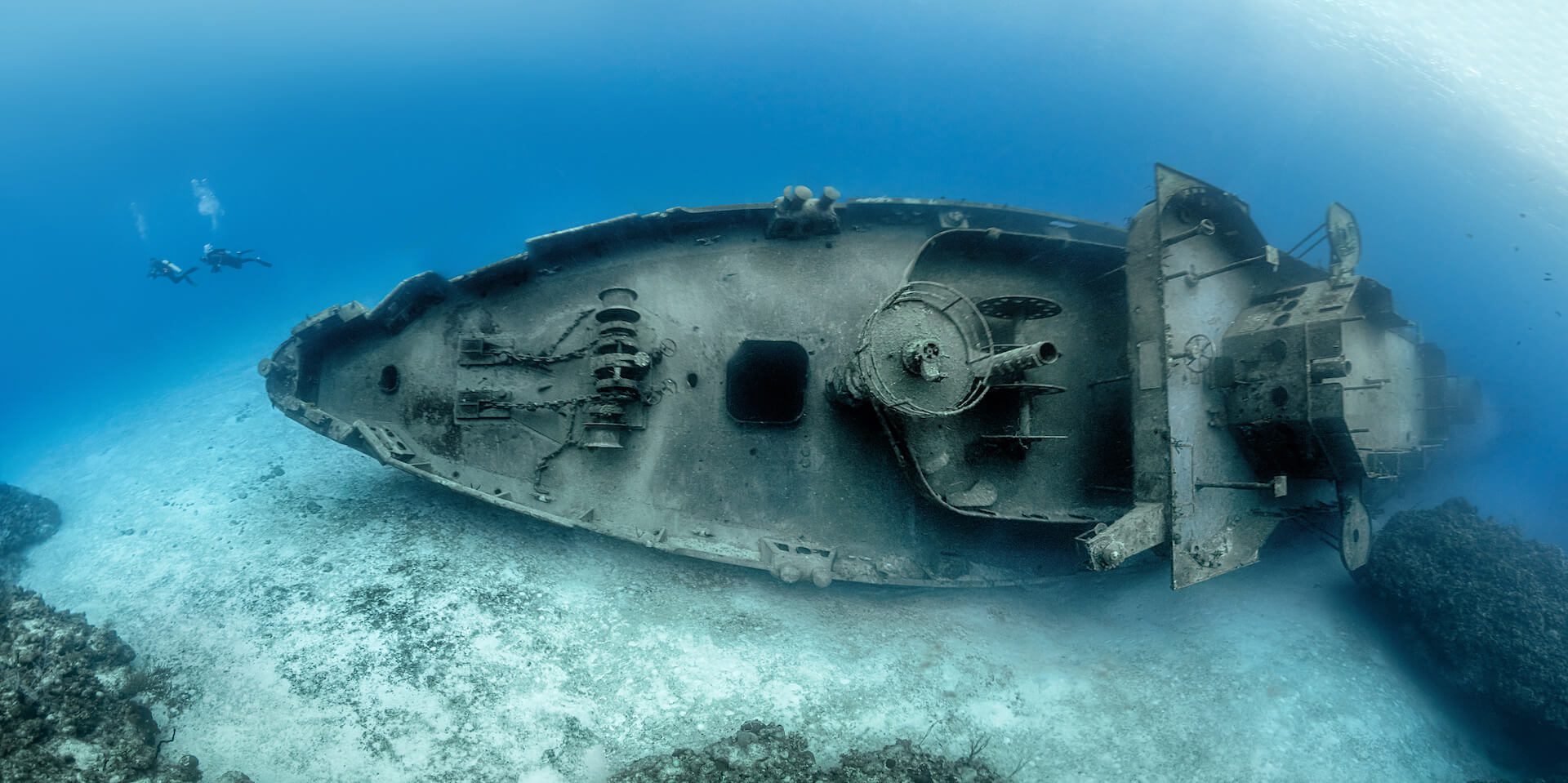 A scuba diver swims under a wrecked boat.