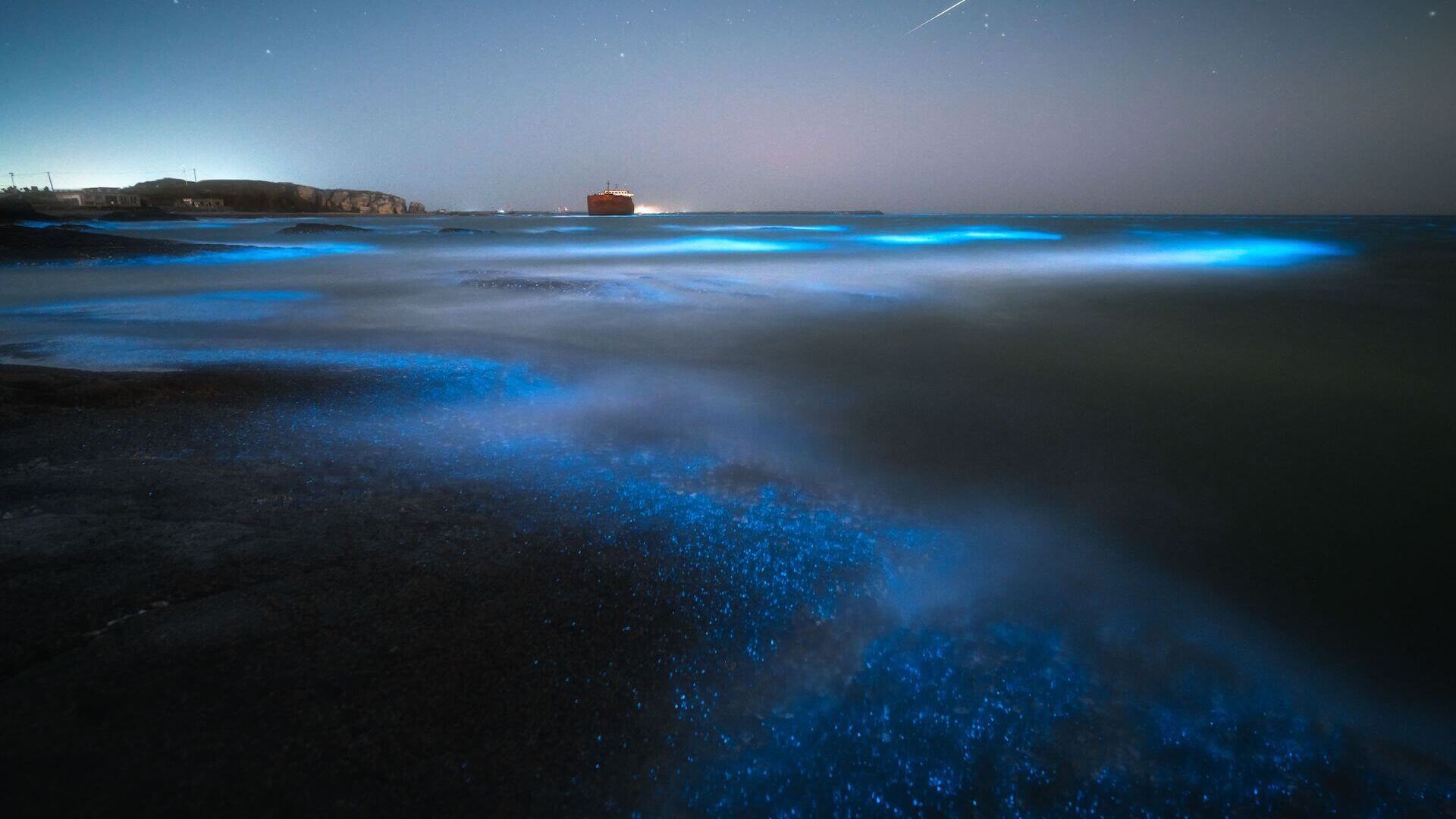 A blue glow on the ocean at night.