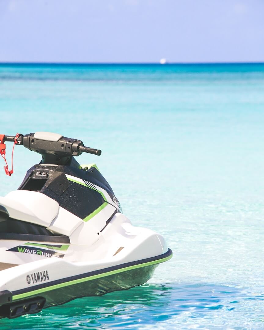 A green and white jet ski in the clear blue water.