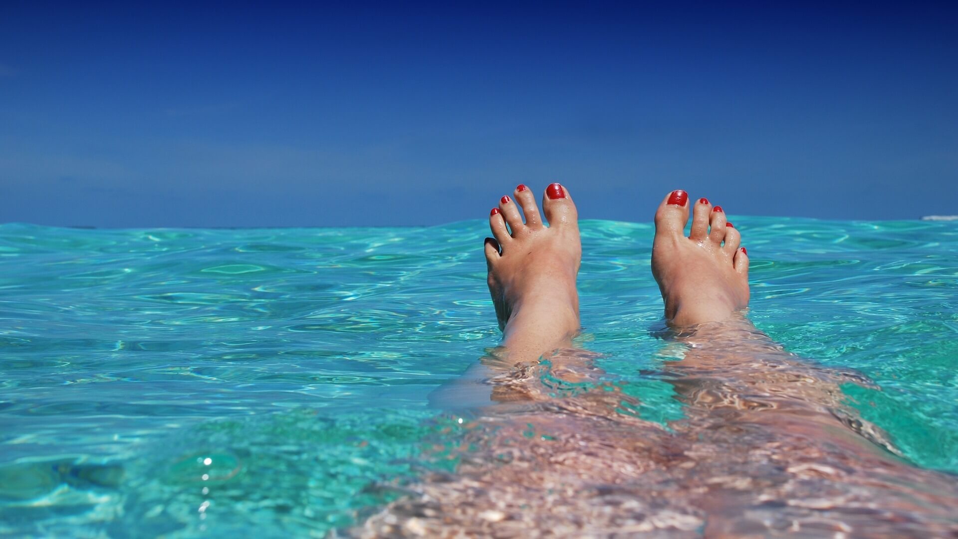A woman's feet in the clear water of the ocean.