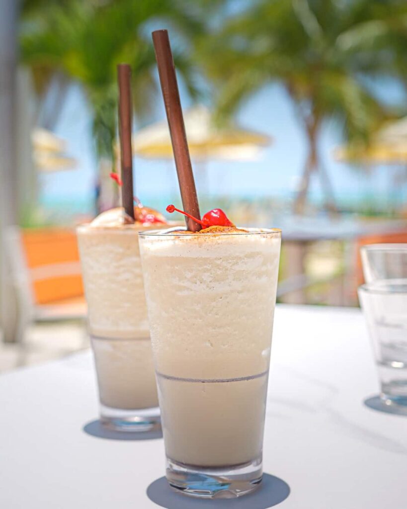 Two Mudslide cocktails, Rum Point Club's signature drink, garnished with cherries, outside at Solis Restaurant.